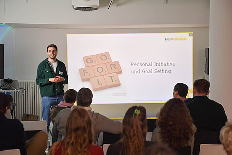 Workshopleiter vor einer PPT-Folie mit dem Schriftzug "Go for it"